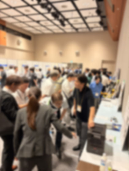 ポータブル蓄電池「剛電」の共同出展ブースに集まる、たくさんの来場者と説明を受ける様子